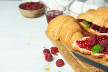 Concept of delicious food with croissants with raspberry jam on white wooden background