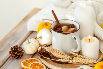 Warm autumn drink with applesand spices: cinnamon, anise. Pumpkin, candle as decor. Cozy home atmosphere.