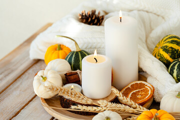 Fototapeta na wymiar Pumpkins and candle with fairy lights around on a wooden table. Autumn season image, cozy home atmosphere. Close up. Thanksgiving family dinner table decor.