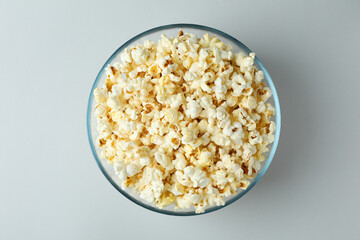 Glass bowl with popcorn on light gray background