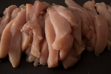 Photo of sliced ​​chicken meat on a dark cutting board with cut marks