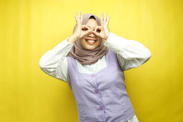 Beautiful asian young muslim woman smiling cheerfully and excitedly, with glasses hands, isolated on yellow background