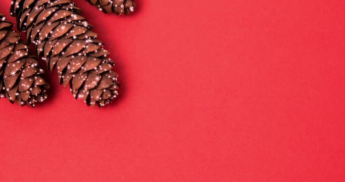 shiny sparkling stars on a pine cone on a red background. pine cone on a red background. new year video background template. screensaver, copy space.