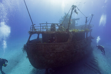 SCUBA divers exploring a shipwreck in tropical waters - obrazy, fototapety, plakaty