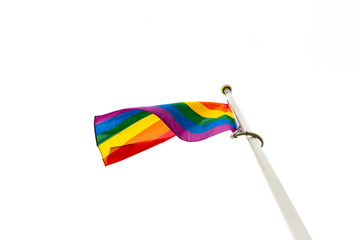 Close up of a rainbow LGBT flag flying against a bright white sky. Suffolk Pride. Concept of happiness freedom love same-sex couple