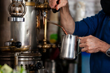 Fototapeta na wymiar Man preparing coffee with an antique coffee maker machine
