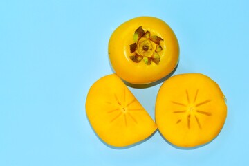 yellow ripe persimmon on blue background, top view
