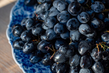 Dark juicy slightly moistened grapes on a plate