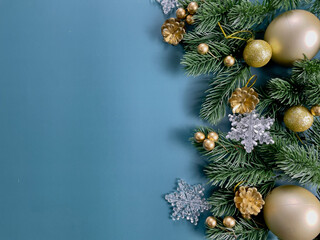 Christmas decorations, pine tree leaves, golden balls, snowflakes, golden berries on blue background