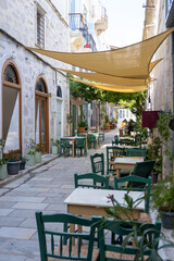 Outdoors cafe tavern tables and wooden chairs at Ermoupoli Syros island Cyclades Greece. Vertical