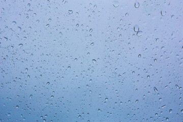 Raindrops on glass against the blue sky.