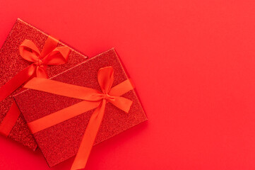 Two gifts in a red package tied with red ribbons on a red background. Stylish composition. Minimalism. Holiday, congratulations, Birthday, Christmas, New Year, Valentine's Day, family celebrations.