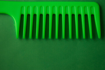 Closeup shot of green hair comb isolated on dark green background
