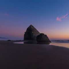 Large and small rocks on the ocean. Beautiful sunset. Blue sky, colored by the orange rays of the setting sun. Calm. There are no people in the photo. There is an empty space for insertion.