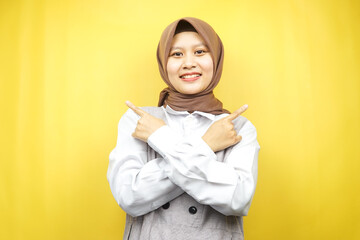 Fototapeta premium Beautiful young asian muslim woman smiling confident, enthusiastic, cheerful with hands pointing empty space presenting something, looking at camera isolated on yellow background, advertising concept