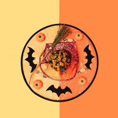 Pumpkins, little rubber pumpkins, broom, bats and candies lay down on witch´s hat, on yellow and orange background. Square geometric flat lay composition, minimmal funny halloween celebration concept