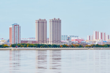 Autumn view of the embankment of Heihe city, China, from the city of Blagoveshchensk, Russia. Reflections of high-rise buildings in the Amur River.