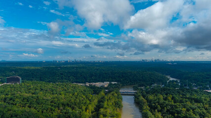 a stunning aerial panoramic shot of the Chattahoochee river surrounded by lush green and autumn colored trees with blue sky and clouds at Cochran Shoals Trail in Marietta USA