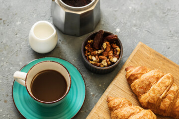 French breakfast. Freshly baked croissants, a cup of coffee, nuts and a milk jug on a concrete table. View from above.