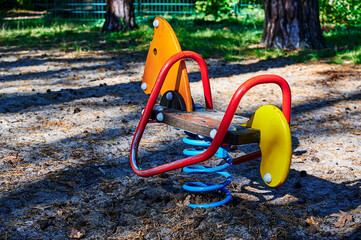 Children's playground with a swing toy in the foreground in a forest in Berlin, Germany.
