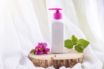 bottle for cosmetics, a rosehip flower and a sprig of mint on a wooden round board. natural cosmetics
