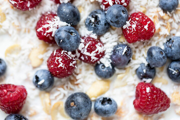 Whole grain oat flakes with fresh ripe blueberries, raspberries, yogurt and vegan almond milk close up. Healthy breakfast concept	