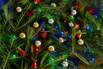 christmas background with fir branches, christmas tree, golden balls, red bells, colored lights