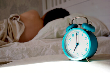 The girl sleeps while the alarm clock rings