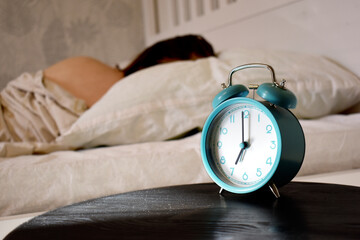 The girl sleeps while the alarm clock rings