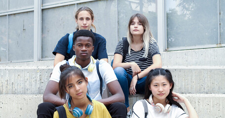Group of 5 teenage multi-ethnic students looking at camera in the schoolyard. Concept: school,...