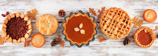 Variety of homemade autumn pies. Apple, pumpkin and pecan. Top view table scene on a white wood banner background. © Jenifoto
