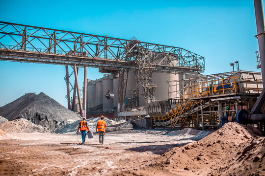 People are working in the industry. Modern technologies work at a cement plant. Technological work on the production of cement. Working atmosphere with copy space. Heaps of sand and soil raw materials