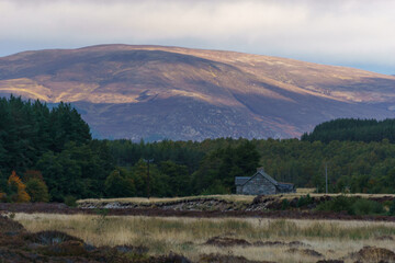 Stone cottage in front of mountain in golden sunlight in the Cairngorms National Park, Scottish Highlands, Scotland, UK - obrazy, fototapety, plakaty