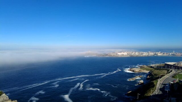 Time lapse fog bank entering Orzán Bay and enveloping the tower of Hercules lighthouse