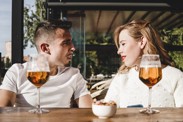 front view of couple having a conversation while drinking beer on a sunny day