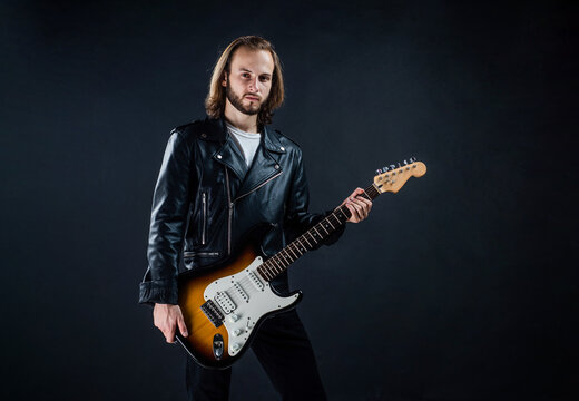 bearded rock musician playing electric guitar in leather jacket, rocker