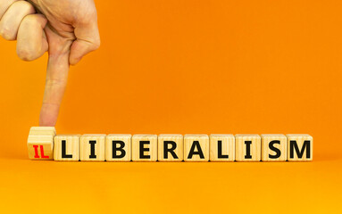 Illiberalism or liberalism symbol. Businessman turns a cube and changes the word 'illiberalism' to...