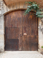 Front view of old wooden door with handle and iron ring and stone lintel. Stone lintel above rustic painted closed door. Architecture and Construction.