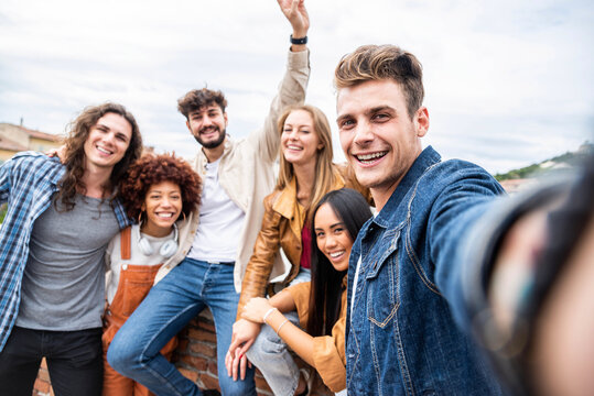 Multiracial happy friends celebrate together taking selfie portrait on city street - Young people having fun laughing together outdoors - Happy lifestyle and friendship concept.