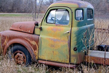 Green truck cab with rusted hood forgotten in a farmer's field. Ottertail Minnesota MN USA