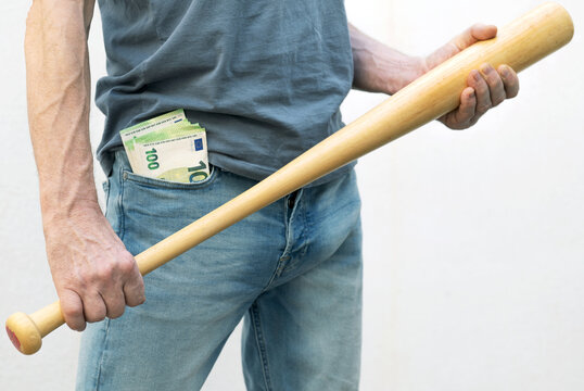 Man with two hundred euros in his jeans pocket, holding a baseball bat, threatening.