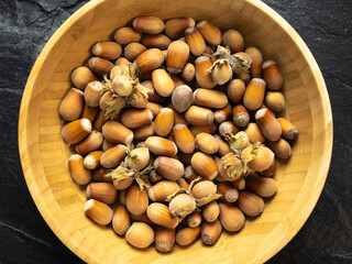 Hazelnuts in a bamboo bowl on a slate work surface, background. Flat lay, top view.