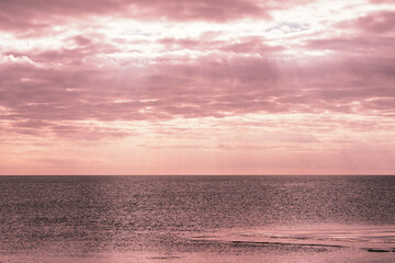 Natural background of cloudy sky over the sea in the morning twilight. The first rays of the sun are barely visible through the clouds. Copy space.