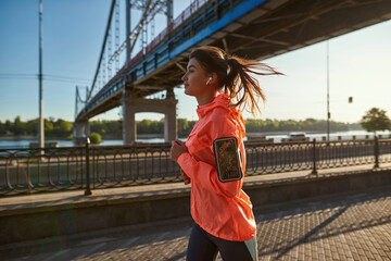 Active female runner jog listen music on cell