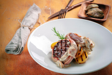 Grilled beef steak baked with bacon with mushroom sauce and potatoes, served on a plate.