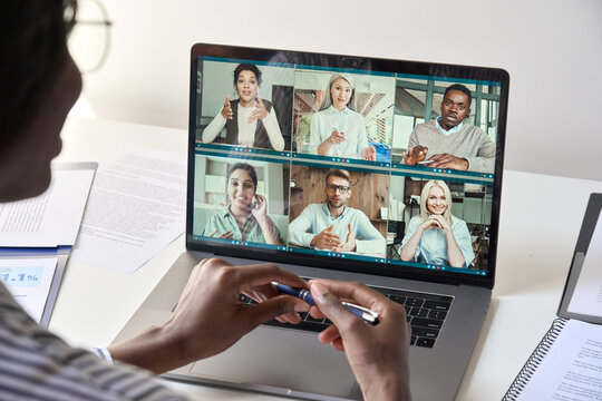 Black Woman Manager Leader Having Team Chat Virtual Meeting Group Video Conference Call With Diverse Business People Remote Working Online At Home Office. Teleconference Concept. Over Shoulder View