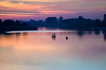 Łódka wędkarze na rzece w pięknym oświetleniu zachodzącego słońca	
