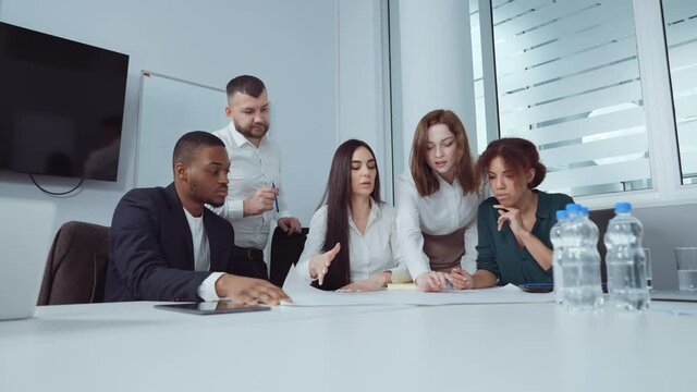 Slow motion group of designers discussing blueprint on paper at office meeting. Tracking shot team working together at new project. Concept of business
