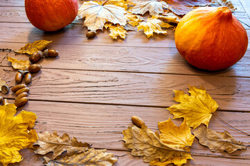 autumn still life of pumpkins, yellow autumn leaves on a brown table.