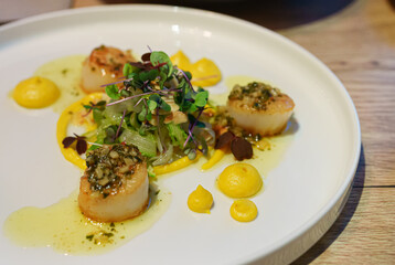 Woman eats scallops in a restaurant.